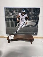 Front view of signed 16x20 photo of Jalen Hurts running with football in Eagles uniform inside acrylic sleeve.