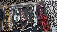 Full view of various necklaces and earrings arranged on fabric with distinct carpet background.