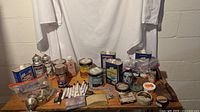Overview of all items on wooden surface showing cans, tins, doorknobs, markers, and plastic bags.