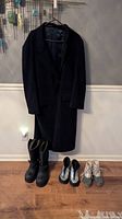 Full view of London Fog men's wool coat hanging on wooden hanger against wall. Four pairs of shoes and boots below the coat on wooden floor. Showing all items in the lot.
