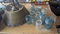 Photo showing metal ceiling lamp and assortment of vintage canning jars arranged on a table.