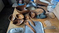 Wood salad set, pewter butter dish lid, aluminum frying pan, wooden utensils, and antique gooseneck lamp all on table