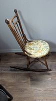 Side profile of vintage bamboo rocking chair showing frame and floral cushioned seat.