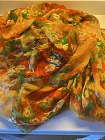 Full view of folded silk chiffon yardage showing floral print and tangerine background