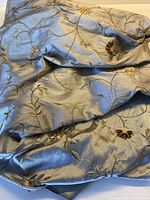 Silvery grey embroidered silk fabric draped to show overall appearance and sheen