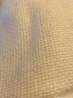 Close view of basket weave texture in pale cream wool fabric