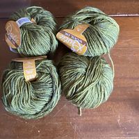 Four balls of variegated green yarn grouped on table