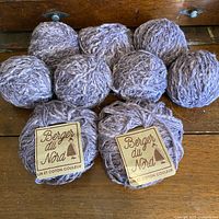 Eight visible balls of dusty lavender Berger du Nord yarn, some labeled
