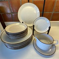 Stack of dinner plates, bread plates, gravy boat on drip plate displayed together