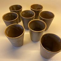 Full set of eight Digoin Grespots stoneware cups displayed upright