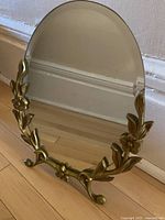 Full view of oval bevelled mirror on ornate floral metal stand