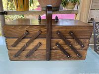 Closed accordion sewing box front view showing scissor arms and handle