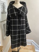 Front view of black wool blend check coat on dress form