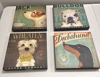 Four dog breed canvas wall art prints laid flat, showing front side with detailed breed illustrations and themed text.