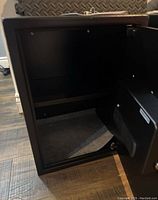 Open view of the inside of the black Stalwart safe showing carpeted base.