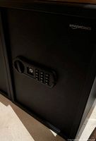 Front view of black AmazonBasics electronic safe with keypad and key lock on door