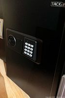 Close-up of the black electronic safe front panel showing the keypad and manual key lock next to it.