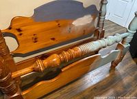 Side view of the pine queen size cannonball bed frame showing turned spindle posts and cannonball finials. Shows unfinished and painted wood areas.