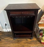 Frontal view of the dark brown wooden wine rack cabinet showing the drawer, hooks, and bottom shelf.