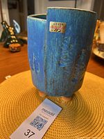 Blue ceramic vase in an irregular shape with Asian style markings and a gold numbered label