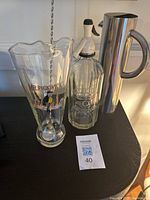 Glass Mr. Pickwick jug with mixing spoon, stainless steel tall water pitcher, and vintage glass soda spritzer.