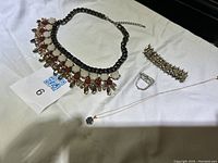 Photo showing all four items: statement necklace, stretchy bracelet, pendant necklace, and vintage brooch.