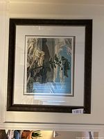 Framed landscape print on wall showing dark wood frame and triple matting