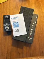 Morley volume pedal and Donner guitar tuner pedal on a wooden surface with MaxSold lot card number 30.