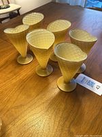 6 yellow cone-shaped glasses with waffle texture on wooden table