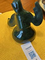 Back view of the heavy dark green jade Inuit carving showing raised arms and detailed coat.