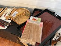 Photo showcasing wooden and lacquered chopsticks in sets, bamboo utensils, and two lacquered trays.