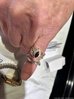 Photo of a hand wearing a silver filigree ring with an oval garnet stone and plain silver band ring on the same hand; displaying the garnet ring prominently