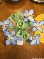 Top view showing blue iris flowers and three candle holders arranged on green metal stems.
