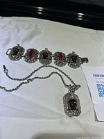 Photo of vintage Selro Selini bracelet and pendant necklace laid flat on white background, showing detailed metalwork and lucite insets