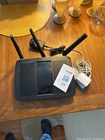 Top view of wireless router with three external antennas and power adapter on wooden table.