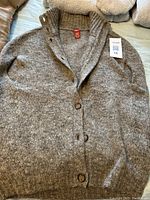 Light brown Olsen mohair and wool knit vest laid flat showing button front and ribbed collar