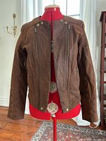 Front view of brown leather jacket on mannequin showing zip details and hardware
