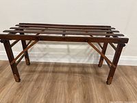 Full front view of antique wooden drying rack showing horizontal slats and legs.