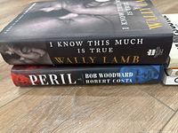 Two hardcover books stacked flat; 'I Know This Much Is True' by Wally Lamb on top, 'Peril' by Bob Woodward and Robert Costa below.