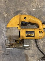 Side view of yellow DeWalt jigsaw with black trigger and metal front showing brand label.