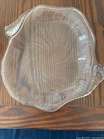 Clear glass platter with two handles or winged edges and swirl texture on wooden surface