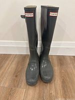 Front view of pair of tall Hunter brand grey gloss rain boots indicating overall shape and color