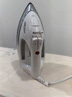 Close-up image of the front view of the white electric steam iron featuring control dials and indicator light.