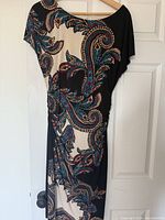 Black dress with paisley blue, red, white pattern on hanging display