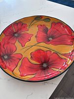 Round serving dish with orange background and red flowers