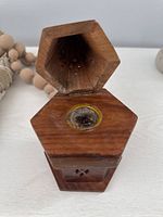 Smaller hexagonal wooden incense holder with burnt incense residue in center and open lid.