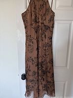 Photo of full dress hanging on door, showing halter neck and floral pattern