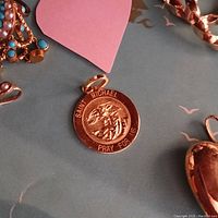 Round gold pendant laid on blue surface among other jewelry