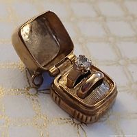Charm with lid open showing ring and band set inside textured interior