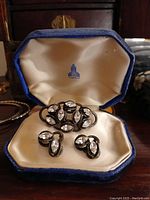 Set of antique rhinestone brooch and screwback earrings displayed in blue velvet box with satin lining and maker's mark, shown from multiple angles.